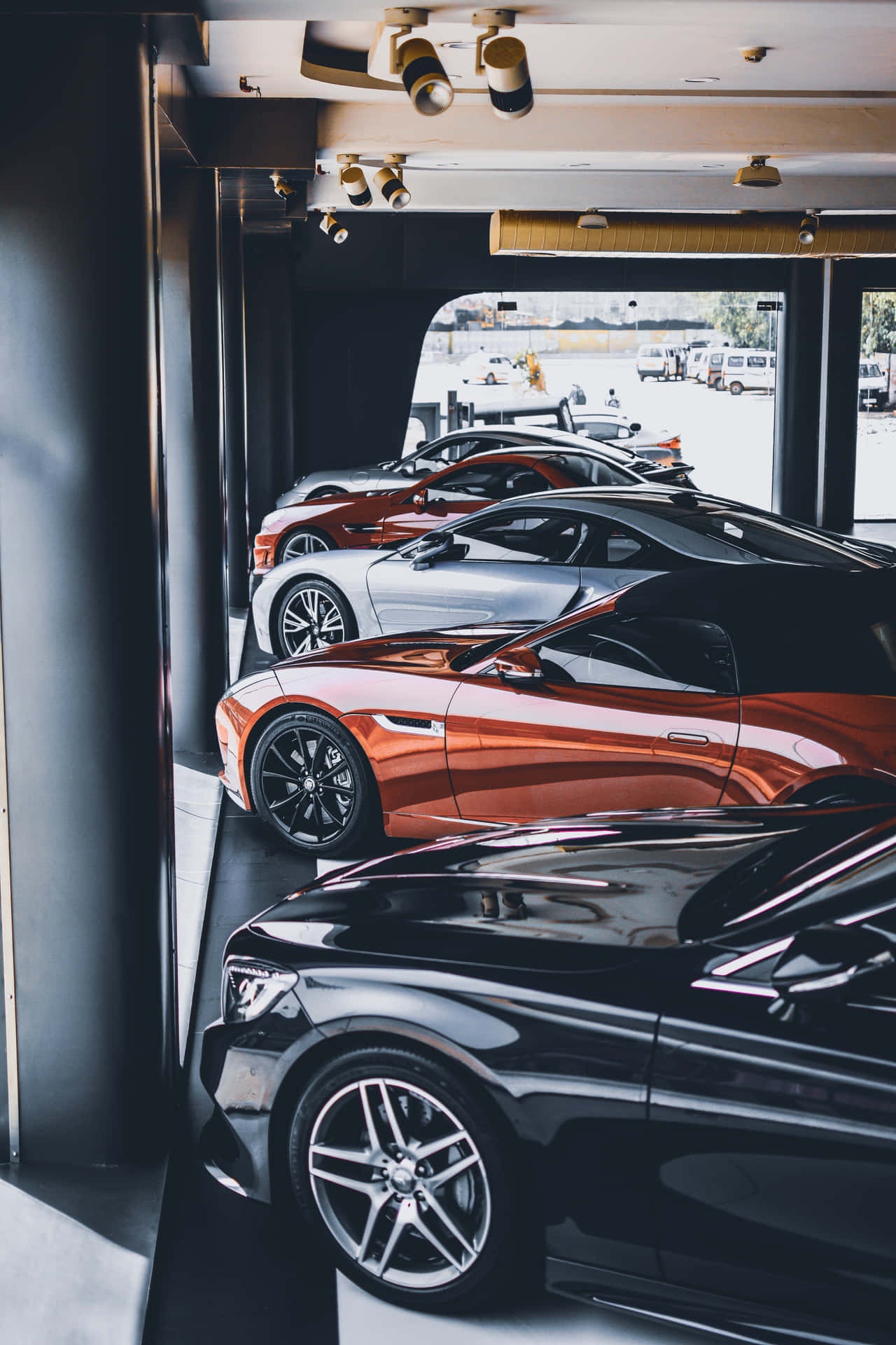 Sleek luxury sports cars in metallic colors displayed in a modern indoor showroom.