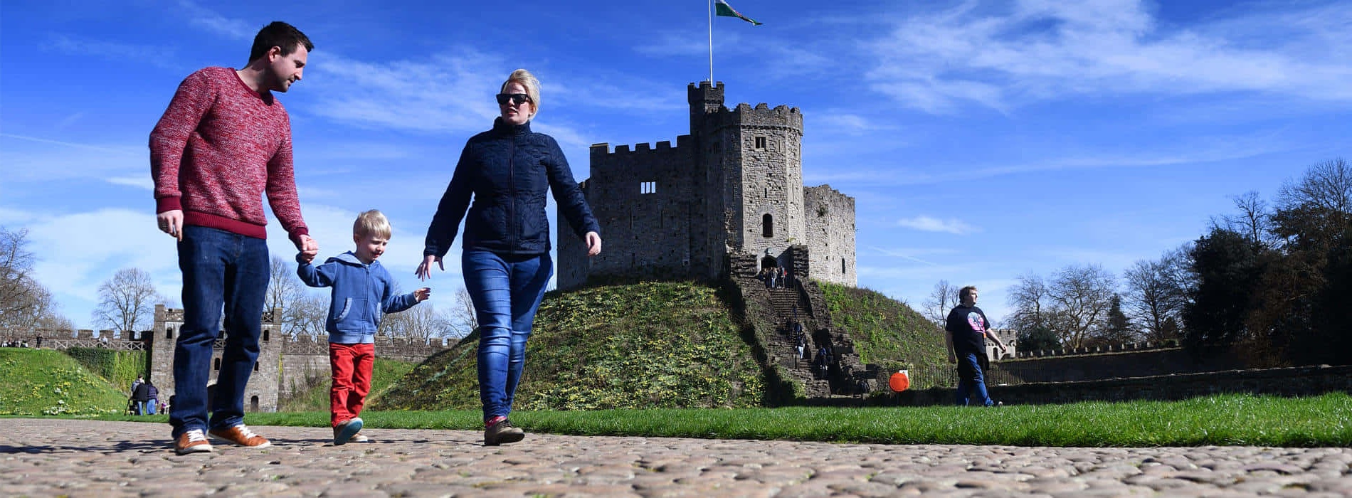 A family walks toward a castle on a sunny day.