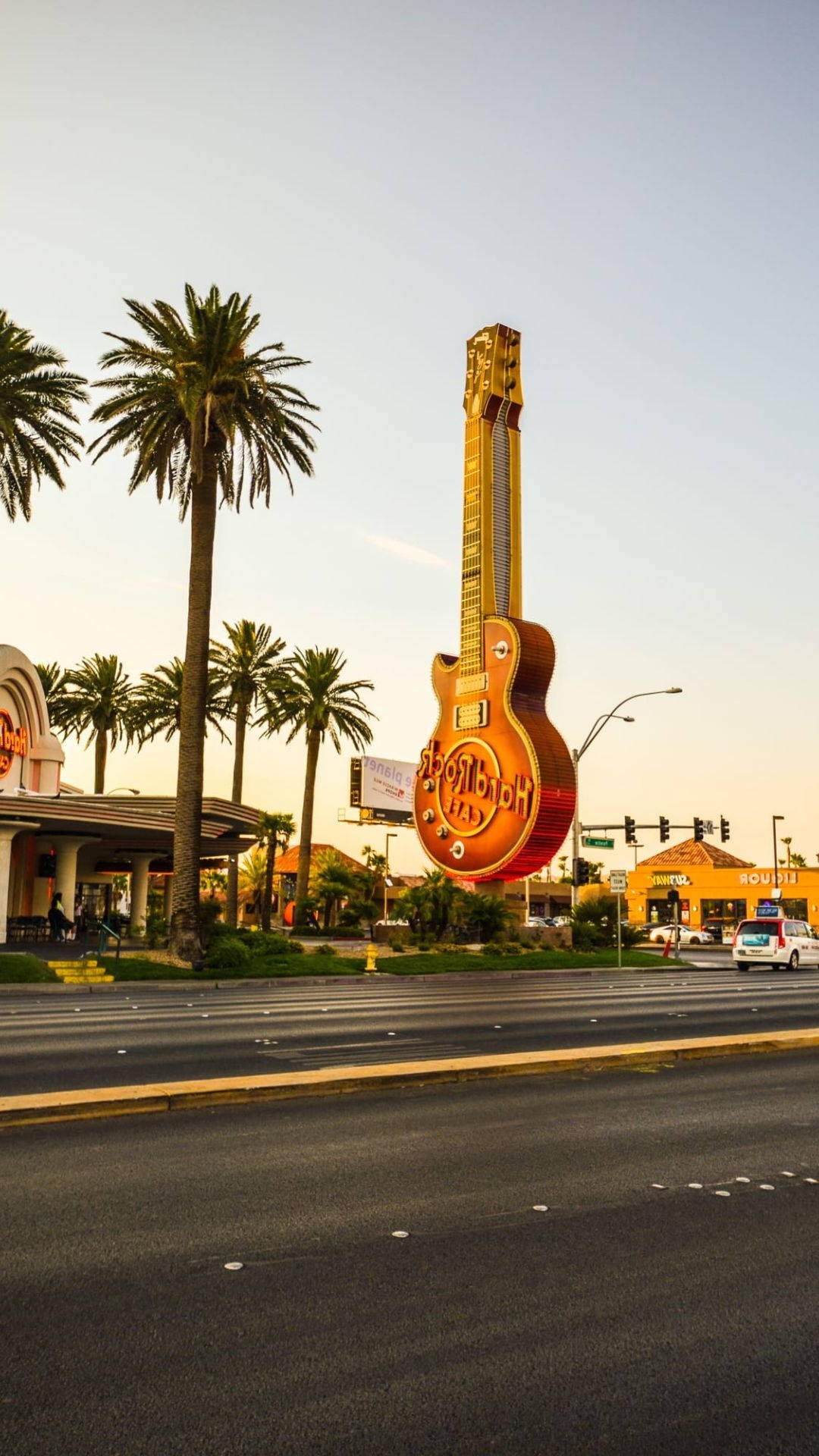 Giant guitar sign on desert highway with palm trees at sunset